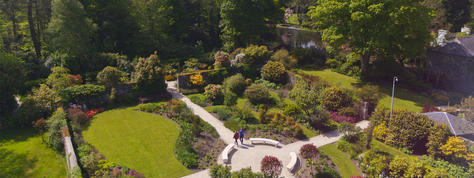 An aerial view of a couple strolling through the gardens of Milntown House as they enjoy a nature holiday on the Isle of Man.